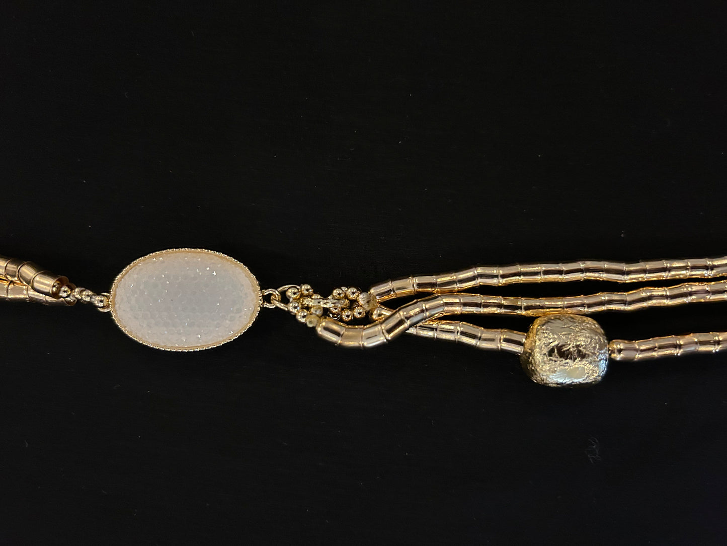 collar dorado con colgante circular u detalles en blanco